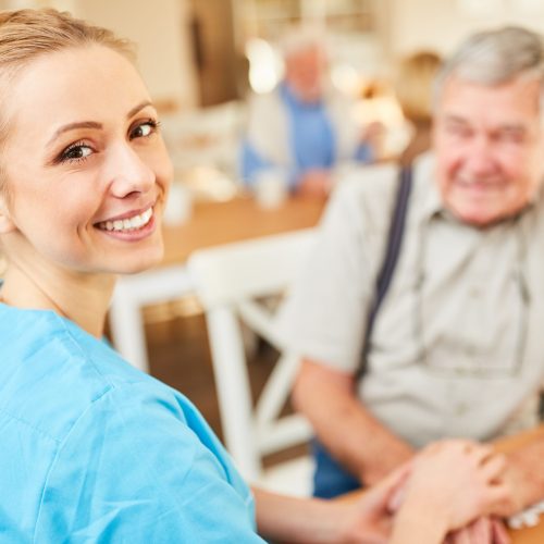 Lächelnde Pflegehilfe Frau oder Altenpfleger tröstet einen Senior im betreuten Wohnen